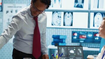 Physician meets with a patient to discuss medical results in a cabinet, using advanced diagnostic equipment to interpret x ray scans, demonstrating a professional healthcare approach. Camera A. video