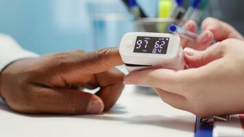 Medical specialist takes the oxygen saturation measurement and checking vital signs during a routine check up with her patient. Medic using an oximeter for accurate readings in office. Camera A. video