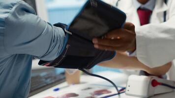 Medical expert taking the pulse and blood pressure with a blood pressure monitor during check up visit, healthcare industry. Physician using modern diagnostic tools for cardiology. Camera A. video
