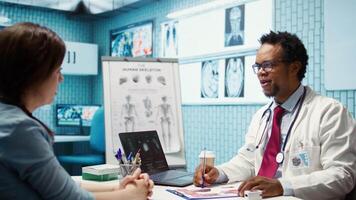 Doctor and patient discussing diagnostic results in a modern medical office, showcasing advanced healthcare technology using a screen displaying x rays and MRI scans. Care management. Camera B. video
