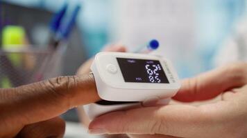 Medical specialist takes the oxygen saturation measurement and checking vital signs during a routine check up with her patient. Medic using an oximeter for accurate readings in office. Camera B. video