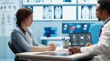 esperto valutare diagnostico risultati con un' paziente nel un' medico mobiletto, in mostra Avanzate assistenza sanitaria tecnologia utilizzando un' schermo visualizzazione X raggi e mri scansioni. cura gestione. telecamera un. video