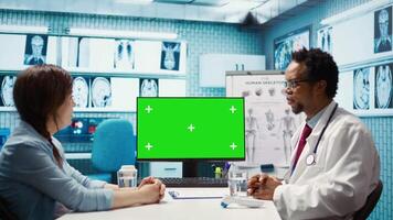 African american medical expert consulting a woman next to copy space on pc screen, pointing at display for a scan interpretation. Male specialist offering professional advice. Camera B. video