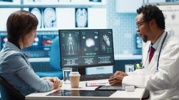 Doctor reading x ray imaging for a diagnostic report at consultation, discussing with a patient about medicine. Physician examining lab test results and analysis, health insurance. Camera A. video