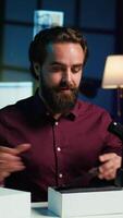 Vertical Entertainer presents smartphone from sponsoring brand, closely analyzing features. Content creator reviewing phone for tech enthusiasts watching his internet channel, inspecting materials, camera B video
