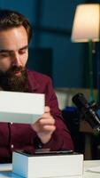 Vertical Tech guru reviewing latest phone, filming internet show in neon lights studio, shooting technology vlog using professional microphone. Vlogger presenting best smartphones on the market, camera A video