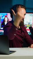 Vertical Expressive media star using microphone to shoot , doing frantic gesturing. Energetic influencer making hectic hand movements while filming vlog with professional mic in home studio, camera A video