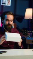 Vertical Content creator receiving mystery box from subscribers, ready to film packaged product unboxing. Internet star pointing to surprise package received, recording in home studio, camera A video