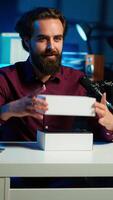 Vertical Tech guru using professional camera to film technology review of new cellphone, doing unboxing . Content creator showing phone box to subscribers, recording with high tech gear, camera A video