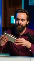 Vertical Man doing technology review of wireless portable speaker for internet vlogging channel. Music playing device held by content creator showing it to his subscribers, camera A video