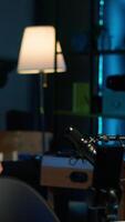 Vertical Content creator adjusting professional microphone in studio before starting vlog, recording with selfie camera. Man in neon lit home studio preparing equipment, filming with smartphone, camera A video