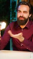 Vertical Tech guru in dimly lit apartment studio filming smart light bulb review for online streaming platforms. Media star hosting show, presenting IoT home automation product, camera A video