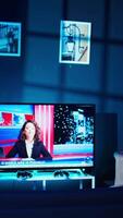 Vertical TV screen showing news broadcast and recording gear in empty home studio interior. Dolly out shot of streaming equipment in modern apartment illuminated with RGB lights at night video
