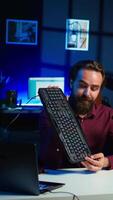Vertical Tech expert testing headphones, mouse and keyboard, reviewing them for online streaming platforms. Internet show host presenting audio device and computer peripherals, camera B video