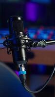 Vertical Close up shot of professional microphone in empty studio illuminated with rgb lights at night, used for internet production. Content creation recording mic in apartment video