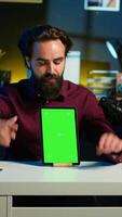 Vertical Tech specialist presenting chroma key tablet in entry level low budget price range to interested viewers, filming in studio. Viral content creator reviewing green screen digital device, camera A video