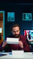 Vertical Tech guru reviewing latest phone, filming internet show in neon lights studio, shooting technology vlog using professional microphone. Vlogger presenting best smartphones on the market, camera B video