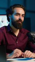 Vertical Content creator adjusting professional microphone in studio before starting recording for online vlogging channel. Man in neon lit home studio using equipment for vlog shooting, camera A video