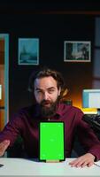 Vertical Tech specialist presenting chroma key tablet in entry level low budget price range to interested viewers, filming in studio. Viral content creator reviewing green screen digital device, camera B video