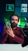 Vertical Portable V mount battery presented by knowledgeable tech professional to audience in studio. Lithium li ion charging device held by content creator doing presentation, camera B video