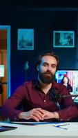 Vertical Content creator adjusting professional microphone in studio before starting recording for online vlogging channel. Man in neon lit home studio using equipment for vlog shooting, camera B video