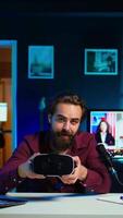 Vertical Technology specialist reviewing VR goggles in RGB lights lit studio. Professional media star filming technology channel vlog for gadget enthusiasts using camera and microphone video