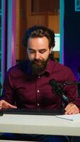Vertical Man filming for online channel in dimly lit home studio, presenting mouse and keyboard to audience. Content creator showing viewers computer peripherals, giving honest opinion, camera A video