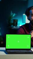 Vertical Entertainer presents chroma key laptop from brand sponsoring , analyzing features. Content creator reviewing green screen notebook for technology enthusiasts, inspecting materials, camera A video