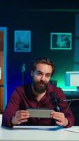 Vertical Cheerful internet star doing technology review of Bluetooth portable speaker for online platforms channel, close up. Jolly influencer presenting music playing device to his viewership, camera B video
