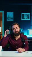Vertical Smiling media star doing technology review of wireless portable speaker for online platforms channel. Cheerful influencer presenting music playing device to his audience, camera B video