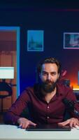 Vertical Influencer in studio endorsing laptop from brand sponsoring , talking in microphone. Content creator does influencer marketing by promoting notebook, recording with high tech mic, camera B video