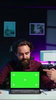 Vertical Man doing live broadcast talking to audience about recent news headlines, reading from chroma key laptop. Online show host presenting information from green screen notebook, camera B video