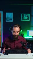 Vertical Man filming for online channel in dimly lit home studio, presenting mouse and keyboard to audience. Content creator showing viewers computer peripherals, giving honest opinion, camera B video