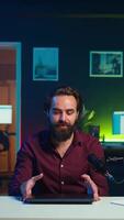 Vertical Tech content creator filming review of newly released gaming laptop, unboxing it and giving feedback to his fanbase. Internet star endorsing sponsor branded device to subscribers, camera B video