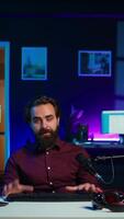 Vertical Man in studio reviewing gaming keyboard received from sponsoring brand. Online show host paid to promote bluetooth wireless computer peripheral to viewers during live broadcast, camera B video