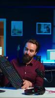 Vertical Influencer in studio reviewing gaming keyboard, mouse and headphones. Online show host filming electronics haul, presenting wired computer peripherals to viewers during live broadcast, camera B video