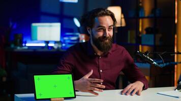 Tech engineer presenting green screen tablet in low budget price range, filming from dimly lit home studio. Content creator reviewing mockup digital device in front of online audience, camera A video