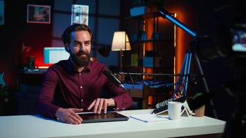 Smiling technology content creator filming review of newly launched gaming laptop, impressed by thinness. Internet star endorsing sponsor branded notebook to subscribers, camera B video
