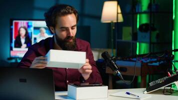 Tech guru reviewing latest phone, filming internet show in neon lights studio, shooting technology vlog using professional microphone. Vlogger presenting best smartphones on the market, camera A video