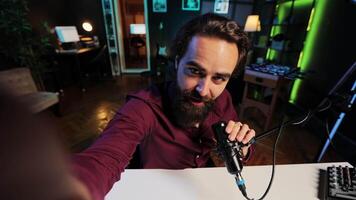 Upbeat content creator hosting online show in rgb lights studio, shooting vlog using selfie camera. POV of cheerful vlogger talking during streaming service broadcast filmed with mobile phone video