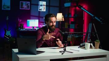 influenciador fala dentro frente em Smartphone em anexo para tripé e Alto qualidade microfone dentro estúdio, discutindo com espectadores. homem usando Móvel telefone e profissional engrenagem para registro social meios de comunicação , Câmera b video