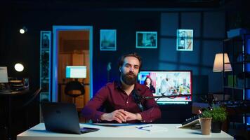 Content creator adjusting professional microphone in studio before starting recording for online vlogging channel. Man in neon lit home studio using equipment for vlog shooting, camera B video