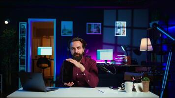 Entertaining man in studio films tablet review for tech enthusiasts. Viral media star hosts technology internet show, unboxing digital portable device, feeling impressed by thinness, camera B video