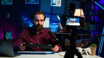 Content creator filming technology review of newly released DJ controller, unboxing it, excited to look at specifications. Influencer showcasing sound mixer device to viewers, camera A video