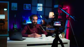 Content creator hosting online show in rgb lights studio, shooting vlog using professional gear. Vlogger presenting informations during streaming service broadcast filmed with camera, camera B video