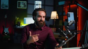 Expressive man using smartphone on selfie stick to shoot , doing frantic gesturing. Animated influencer making hectic hand movements while filming vlog with phone in studio, camera B video