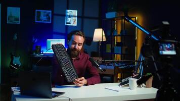 Tech expert testing headphones, mouse and keyboard, reviewing them for online streaming platforms. Internet show host presenting audio device and computer peripherals, camera B video