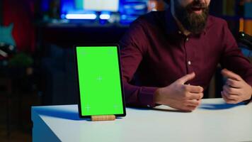 Happy influencer in studio filming chroma key tablet review for tech enthusiasts. Joyful media star hosts technology internet show, unboxing isolated screen digital portable device, camera A close up video