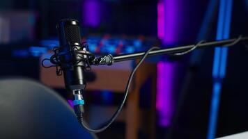 Close up shot of professional microphone in empty studio illuminated with rgb lights at night, used for internet production. Content creation recording mic in apartment video