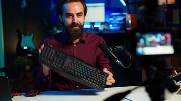 Tech expert testing headphones, mouse and keyboard, reviewing them for online streaming platforms. Internet show host presenting audio device and computer peripherals, camera A video